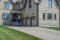 a gray and brick house on the corner of a sidewalk with grass in front of it