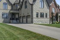 a gray and brick house on the corner of a sidewalk with grass in front of it