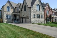 a gray and brick house on the corner of a sidewalk with grass in front of it