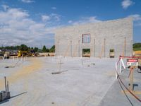 a gray building being built by a blue sky and clouds in the background with red string around the edge