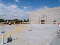 a gray building being built by a blue sky and clouds in the background with red string around the edge