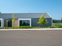 a building is painted gray outside with a white trimming and trees in the yard