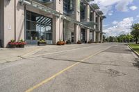 a gray fire hydrant in the middle of street with an office building behind it