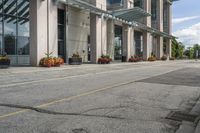 a gray fire hydrant in the middle of street with an office building behind it