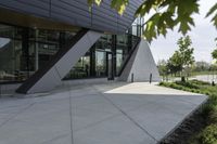 the entrance to the building is gray and white with black accents on it and bushes