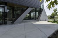 the entrance to the building is gray and white with black accents on it and bushes