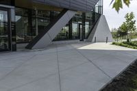 the entrance to the building is gray and white with black accents on it and bushes