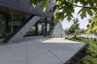 the entrance to the building is gray and white with black accents on it and bushes