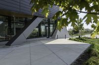 the entrance to the building is gray and white with black accents on it and bushes