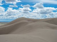 man riding horse through the middle of the dunes on a sunny day on a partly cloudy day