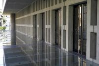 a long hallway with many glass doors in it and concrete walls on both sides of the corridor