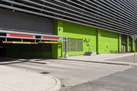 an empty parking area and a green building on a sunny day in the sun,