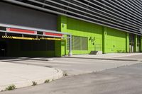 an empty parking area and a green building on a sunny day in the sun,