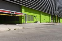 an empty parking area and a green building on a sunny day in the sun,