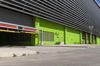 an empty parking area and a green building on a sunny day in the sun,