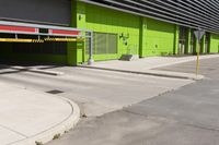 an empty parking area and a green building on a sunny day in the sun,