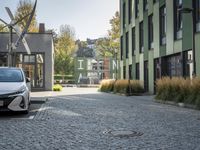 the car is parked near the green buildings on the street for parking and transportation purposes