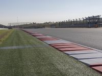 an empty track at a motorsports club with some red and white stripeing on it