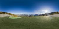 the green grass is flowing through the mountains and sand dunes of a sandy area with a small pond