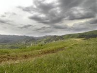 a person with their back pack walking down a mountain road over green hills and a steep grassy area