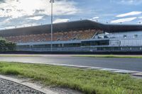 a green motorcycle parked at the front of a large building with a track in front