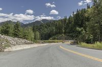 a scenic road is lined by lush green trees and mountains in the distance, on a sunny day