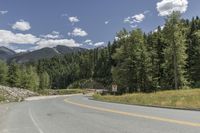 a scenic road is lined by lush green trees and mountains in the distance, on a sunny day