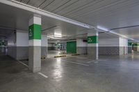 a green and white parking garage has several signs on the walls that point to the left