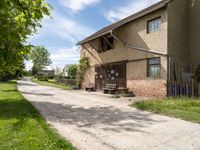 a brick building with a bench in front of it and a road leading towards it