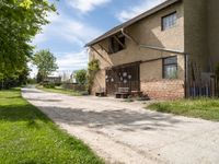 a brick building with a bench in front of it and a road leading towards it