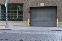 two fire hydrants on the sidewalk in front of a large brick building with many windows