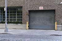 two fire hydrants on the sidewalk in front of a large brick building with many windows