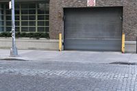 two fire hydrants on the sidewalk in front of a large brick building with many windows