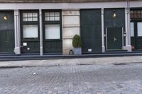 an empty street with an outside bench and green doors on it with windows and planters