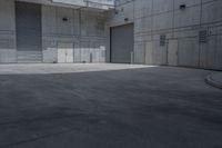 a person on a skateboard in an empty area between buildings and a walkway with a building