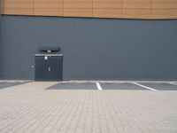 a wall and parking lot in front of a building with a door open on the side