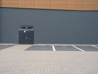 a wall and parking lot in front of a building with a door open on the side