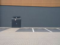 a wall and parking lot in front of a building with a door open on the side