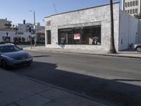 a grey car drives by a building on the corner of a street with a large sign that reads don't stop