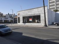 a grey car drives by a building on the corner of a street with a large sign that reads don't stop