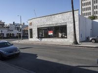 a grey car drives by a building on the corner of a street with a large sign that reads don't stop