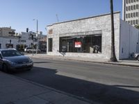 a grey car drives by a building on the corner of a street with a large sign that reads don't stop