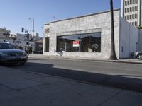 a grey car drives by a building on the corner of a street with a large sign that reads don't stop