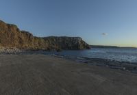 some rocks and a view of the water and a large mountain by the beach or shore