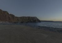 some rocks and a view of the water and a large mountain by the beach or shore