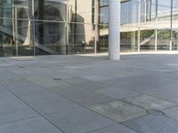 this is an empty sidewalk near a large building with a few glass windows on the side