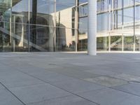 this is an empty sidewalk near a large building with a few glass windows on the side