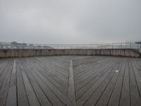 a view of a deck with a bridge in the background and a cloudy sky above