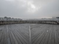 a view of a deck with a bridge in the background and a cloudy sky above