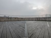 a view of a deck with a bridge in the background and a cloudy sky above